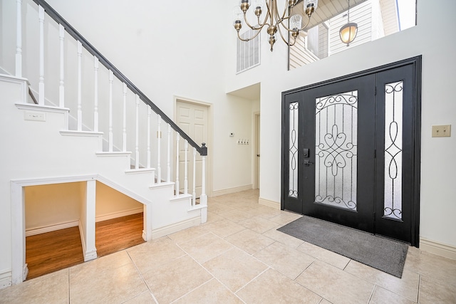 foyer featuring a notable chandelier, a towering ceiling, and light wood-type flooring