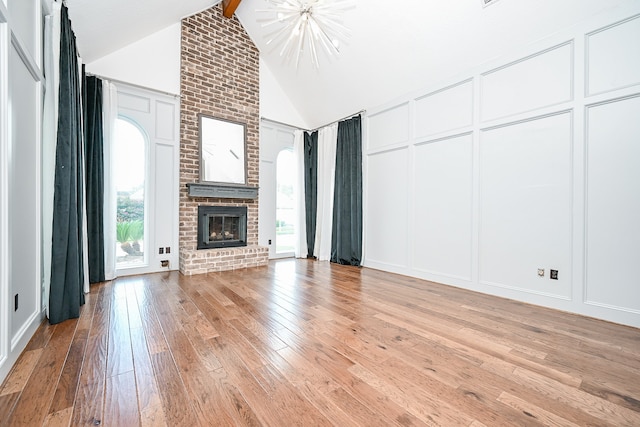 unfurnished living room with light wood-type flooring, vaulted ceiling with beams, and a brick fireplace