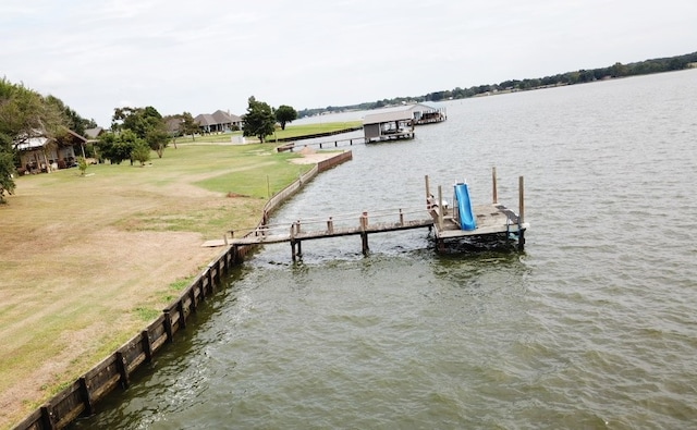 view of dock featuring a lawn and a water view