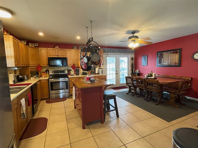 kitchen featuring ceiling fan, light tile patterned floors, a kitchen island, french doors, and black appliances