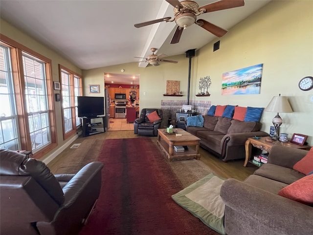 living room with vaulted ceiling, ceiling fan, and a wood stove