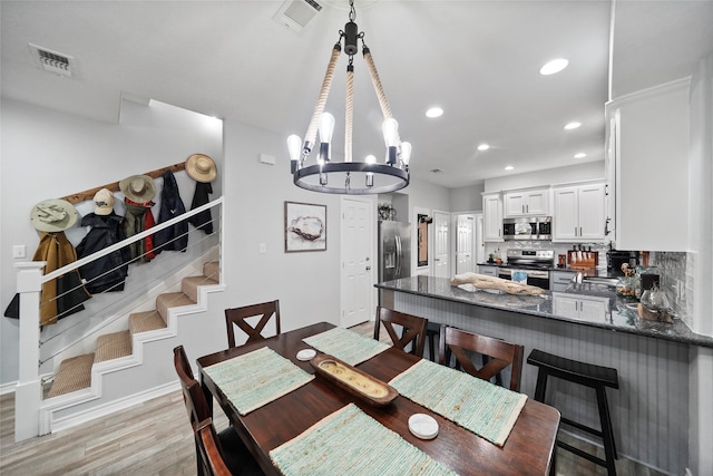 dining room with light hardwood / wood-style floors and a chandelier