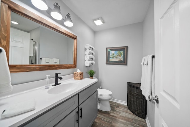 bathroom with wood-type flooring, vanity, a shower with shower door, and toilet