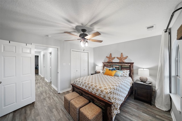 bedroom with a closet, ceiling fan, dark wood-type flooring, and a textured ceiling