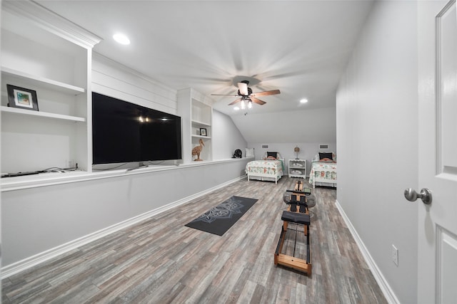 interior space with ceiling fan, built in features, vaulted ceiling, and wood-type flooring