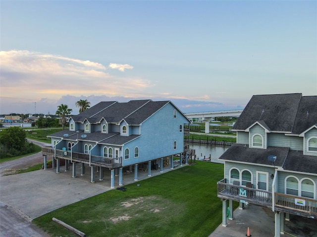 back house at dusk with a water view and a yard