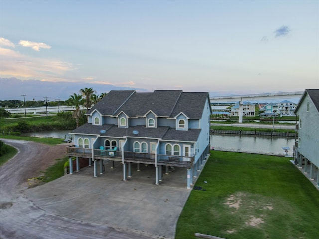 view of front facade with a lawn, a water view, and a carport