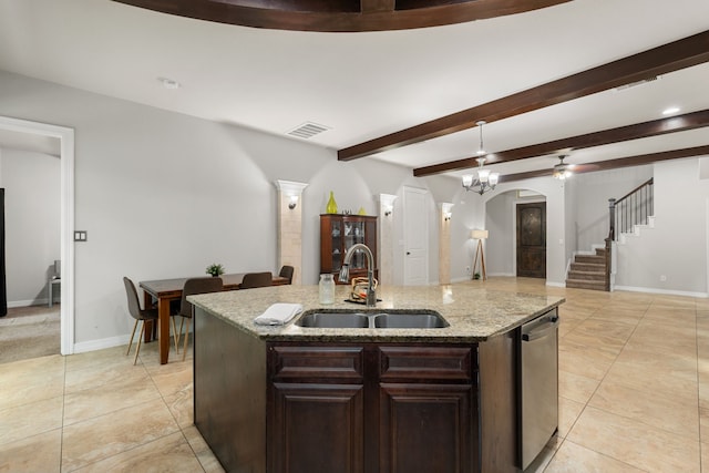 kitchen featuring dark brown cabinetry, sink, a kitchen island with sink, decorative light fixtures, and light stone countertops