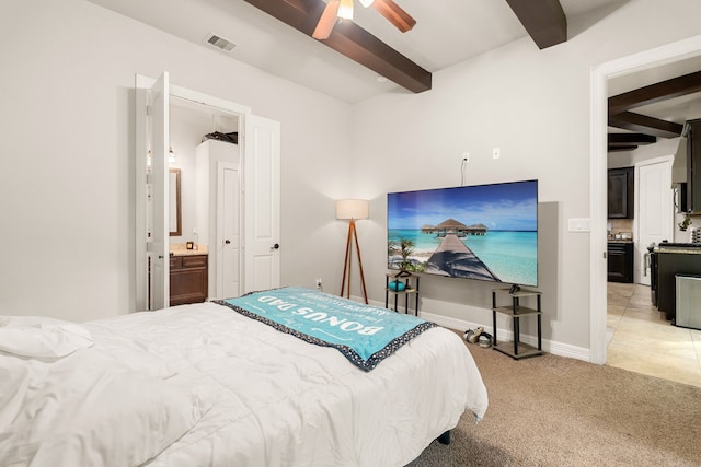 carpeted bedroom featuring ceiling fan, ensuite bathroom, and beam ceiling