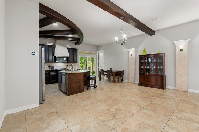 kitchen with decorative light fixtures, a center island with sink, a chandelier, appliances with stainless steel finishes, and a breakfast bar area