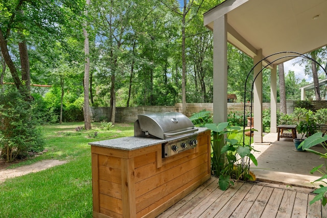 deck with an outdoor kitchen, a grill, and a yard