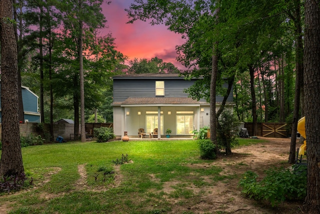 back house at dusk with a yard and a patio