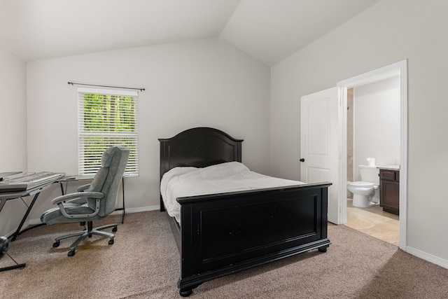 carpeted bedroom featuring lofted ceiling and ensuite bath