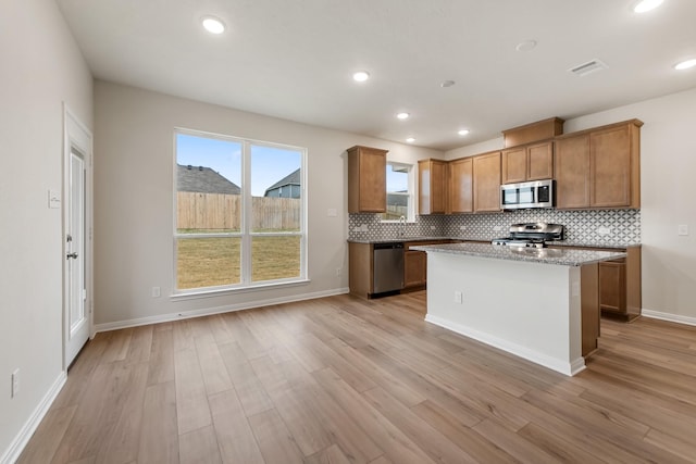 kitchen featuring decorative backsplash, a kitchen island, light hardwood / wood-style floors, and appliances with stainless steel finishes