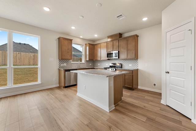 kitchen featuring sink, appliances with stainless steel finishes, a kitchen island, light hardwood / wood-style floors, and decorative backsplash