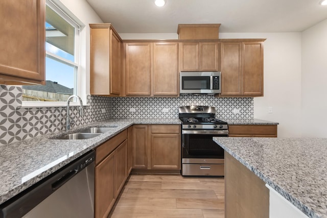 kitchen featuring sink, light hardwood / wood-style flooring, appliances with stainless steel finishes, light stone countertops, and backsplash