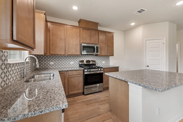 kitchen featuring light stone countertops, stainless steel appliances, sink, and a center island