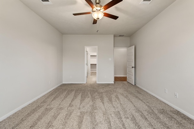 unfurnished bedroom featuring light carpet, a spacious closet, and ceiling fan