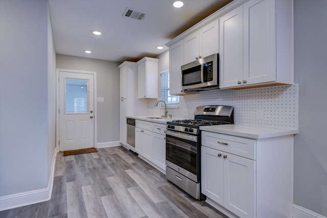 kitchen with sink, light hardwood / wood-style flooring, stainless steel appliances, and white cabinets