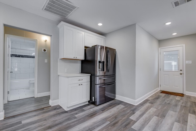 kitchen featuring stainless steel refrigerator with ice dispenser, light hardwood / wood-style floors, white cabinetry, and tasteful backsplash