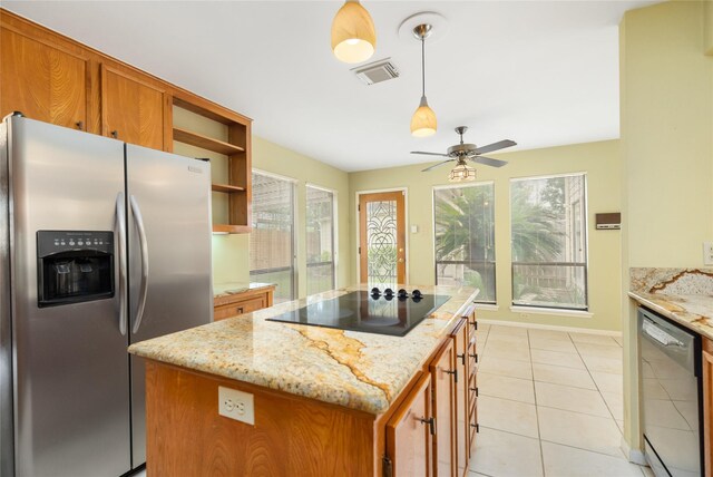 kitchen with hanging light fixtures, light stone counters, stainless steel appliances, a center island, and ceiling fan