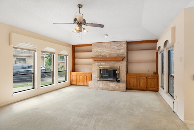 unfurnished living room featuring built in features, a fireplace, ceiling fan, and light colored carpet