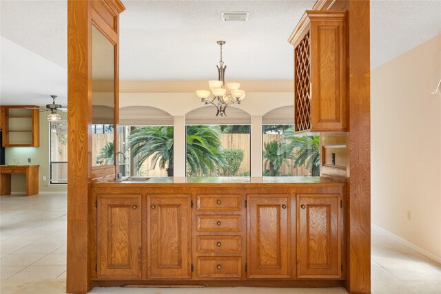 kitchen with ceiling fan with notable chandelier, sink, light tile patterned floors, and decorative light fixtures