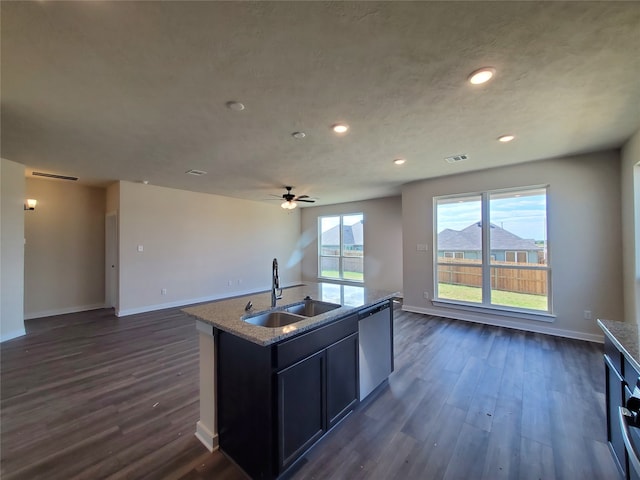 kitchen with stainless steel dishwasher, ceiling fan, dark wood-type flooring, sink, and a center island with sink