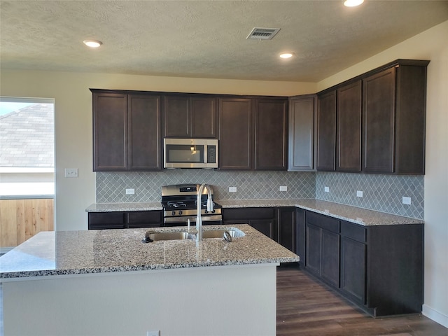 kitchen with dark hardwood / wood-style floors, light stone countertops, sink, and appliances with stainless steel finishes