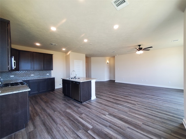 kitchen with tasteful backsplash, dark brown cabinets, sink, a center island with sink, and dark hardwood / wood-style floors