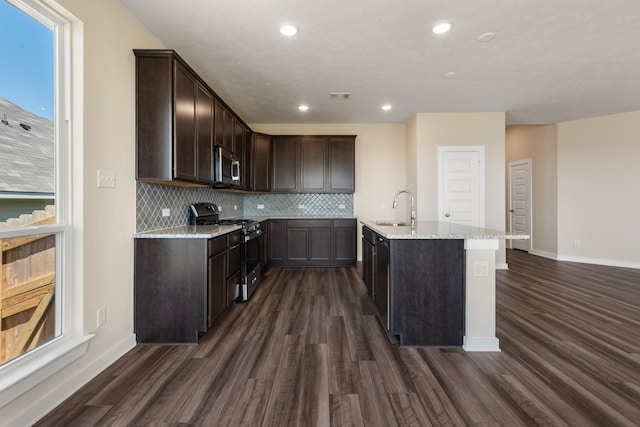 kitchen with dark wood finished floors, stainless steel appliances, visible vents, a sink, and dark brown cabinetry