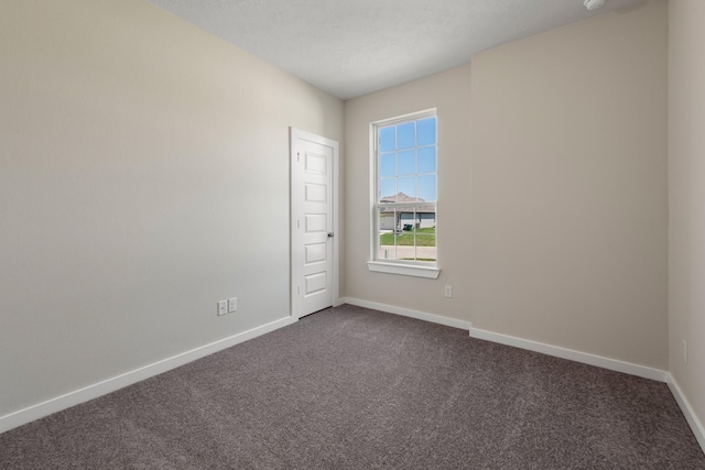 spare room with dark carpet and baseboards
