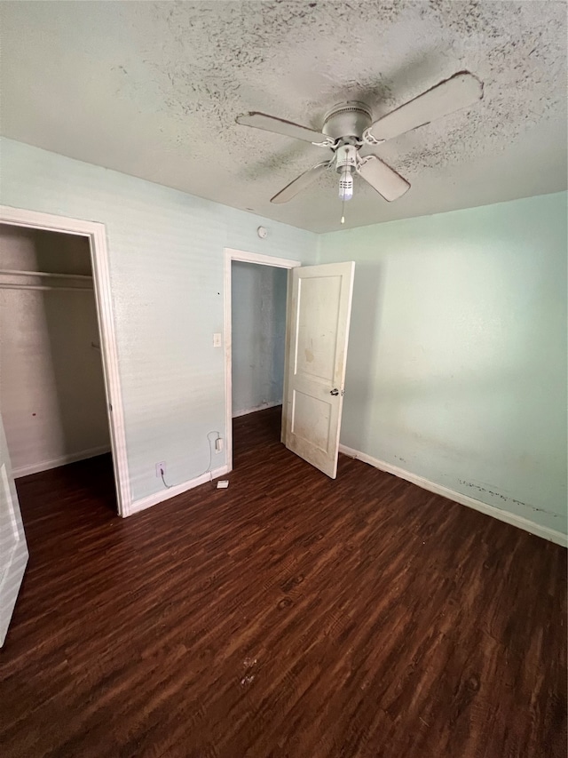 unfurnished bedroom with a closet, ceiling fan, a textured ceiling, and dark hardwood / wood-style flooring