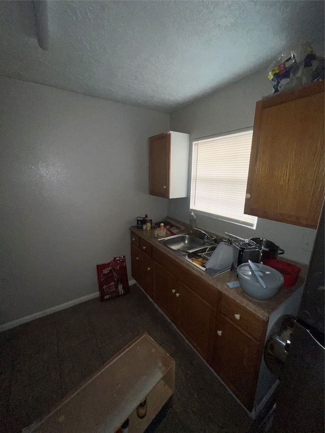 kitchen featuring a textured ceiling, sink, and dark tile patterned floors