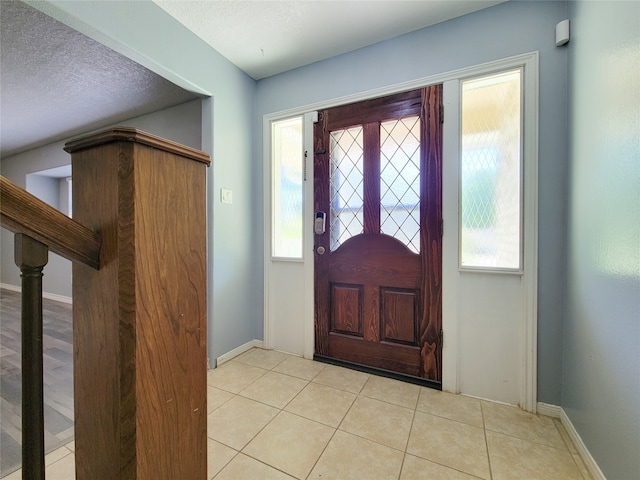 tiled foyer featuring a textured ceiling and a healthy amount of sunlight