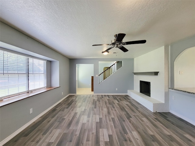 unfurnished living room with ceiling fan, a textured ceiling, and dark hardwood / wood-style floors