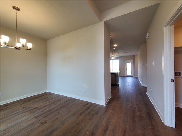 spare room with ceiling fan with notable chandelier and dark wood-type flooring