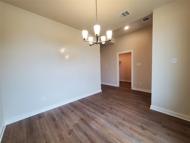 spare room with dark wood-type flooring and a notable chandelier