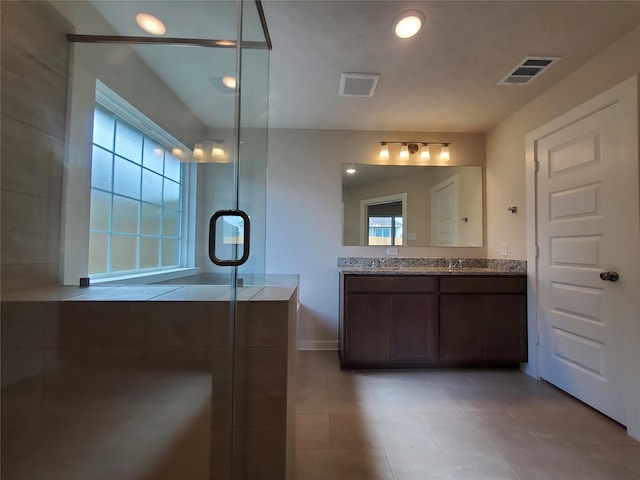 bathroom with vanity, a healthy amount of sunlight, and walk in shower