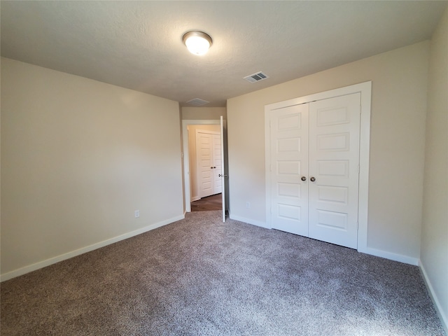 unfurnished bedroom with a closet, a textured ceiling, and dark colored carpet