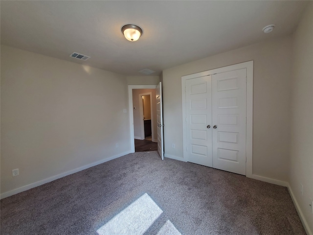 unfurnished bedroom featuring dark carpet and a closet