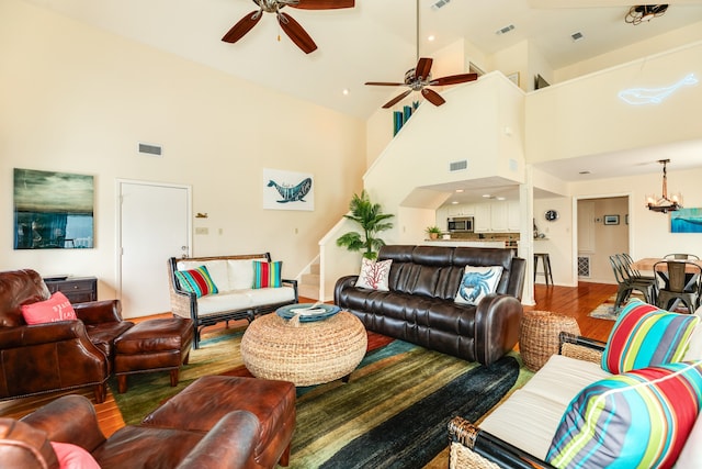 living room featuring ceiling fan with notable chandelier, a high ceiling, and hardwood / wood-style floors