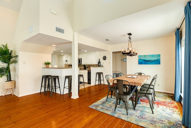 dining space with an inviting chandelier, light wood-type flooring, and a high ceiling