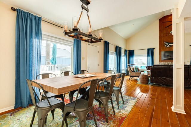 dining area with a notable chandelier, lofted ceiling, and dark hardwood / wood-style flooring