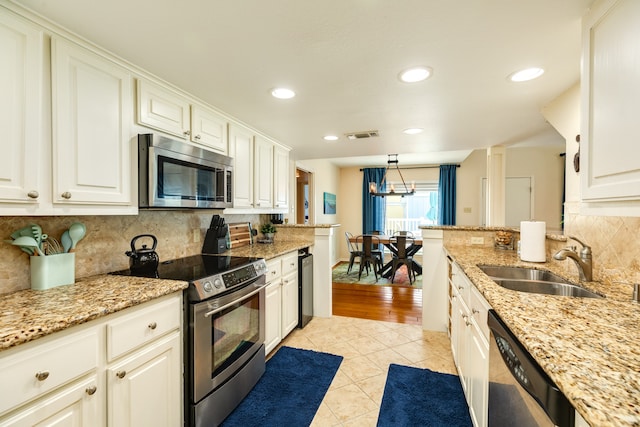 kitchen with light stone counters, light hardwood / wood-style floors, sink, white cabinetry, and stainless steel appliances