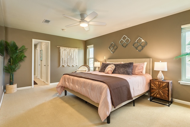 bedroom with ceiling fan, light carpet, and multiple windows