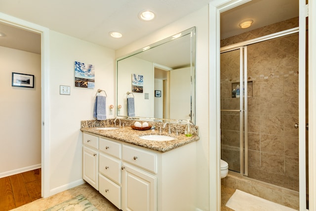 bathroom featuring wood-type flooring, walk in shower, vanity, and toilet