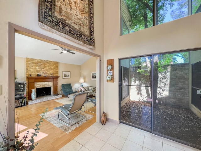 living room with tile patterned floors, ceiling fan, a large fireplace, and high vaulted ceiling