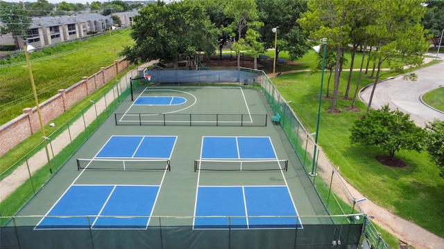 view of tennis court with a lawn and basketball hoop