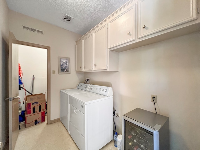 washroom with cabinets, a textured ceiling, and washing machine and clothes dryer